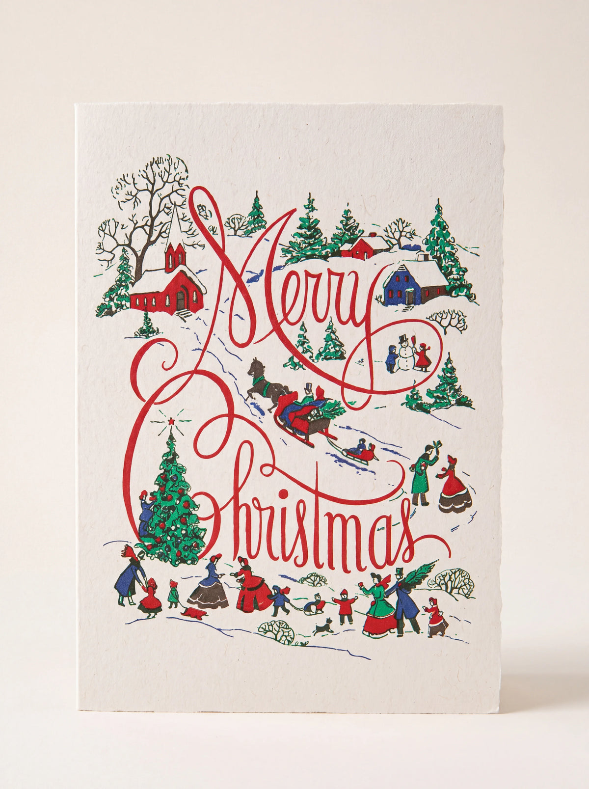 Christmas card with an illustrated winter village scene and red script reading Merry Christmas