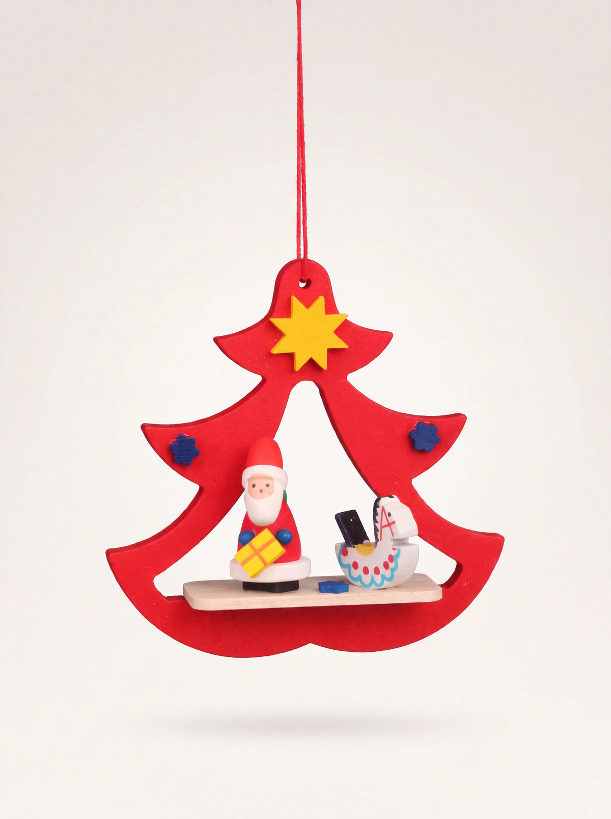 Red wooden tree-shaped Christmas ornament with a miniature Santa figure inside the cut-out frame
