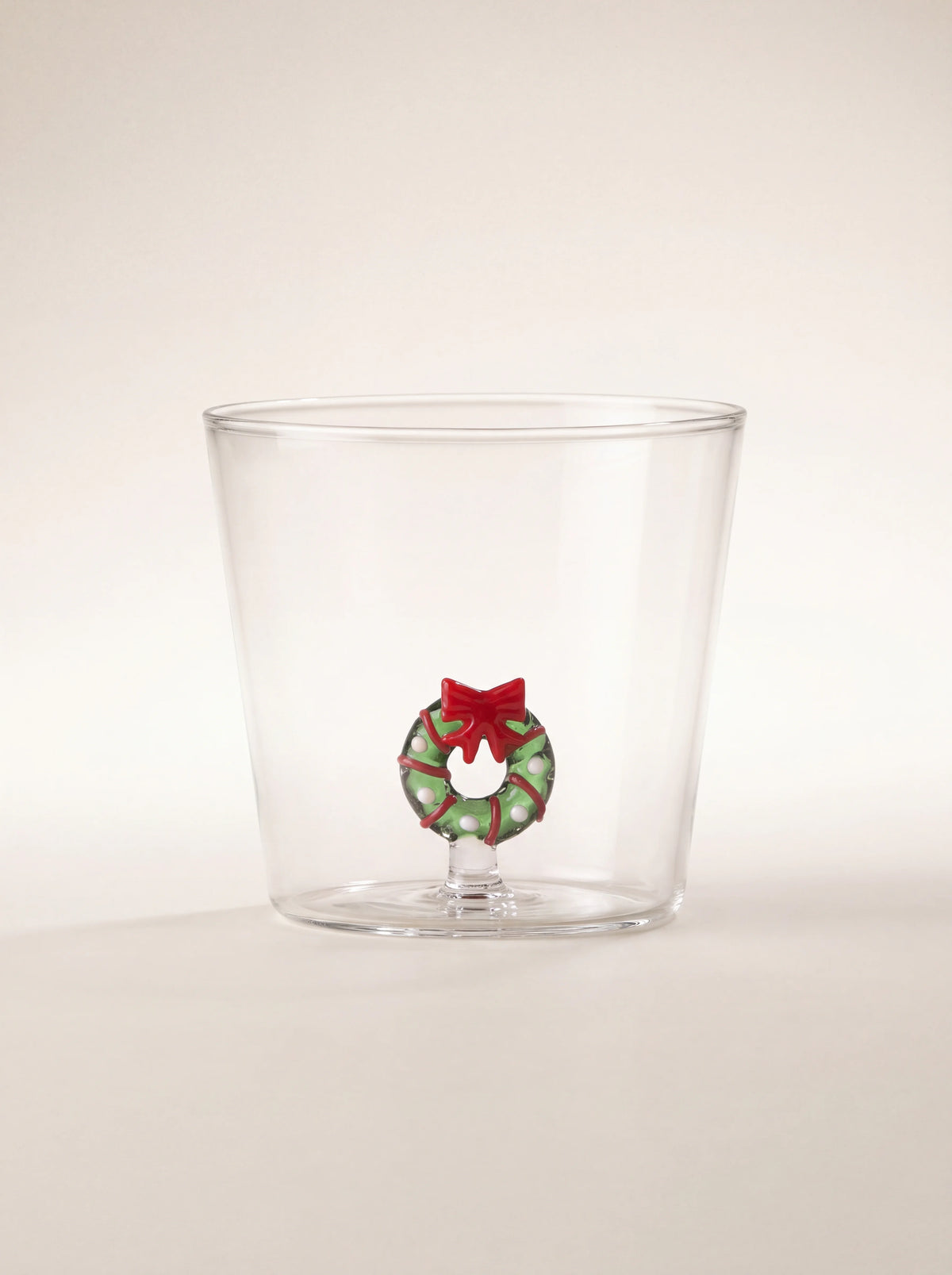 Clear borosilicate glass tumbler with a miniature green Christmas wreath and red bow inside the base
