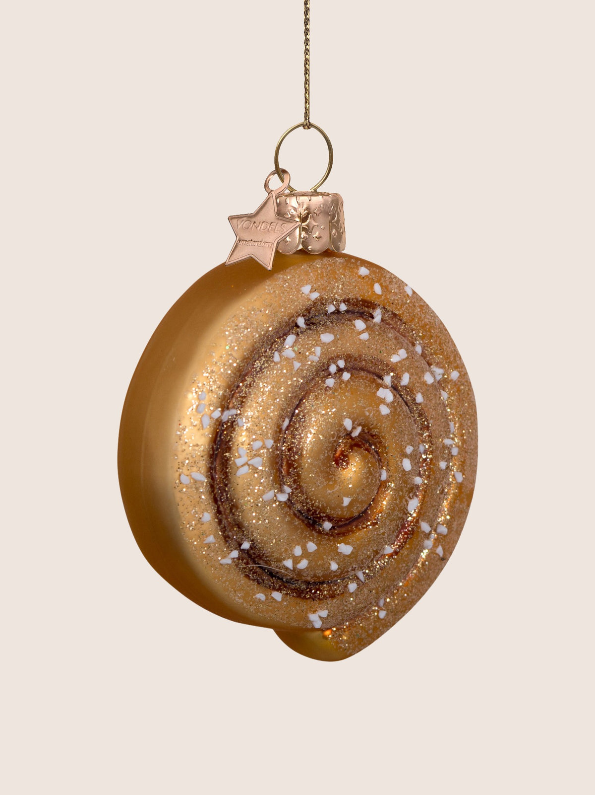 Three-quarter view showing the curved disc shape and raised surface details of the cinnamon roll ornament