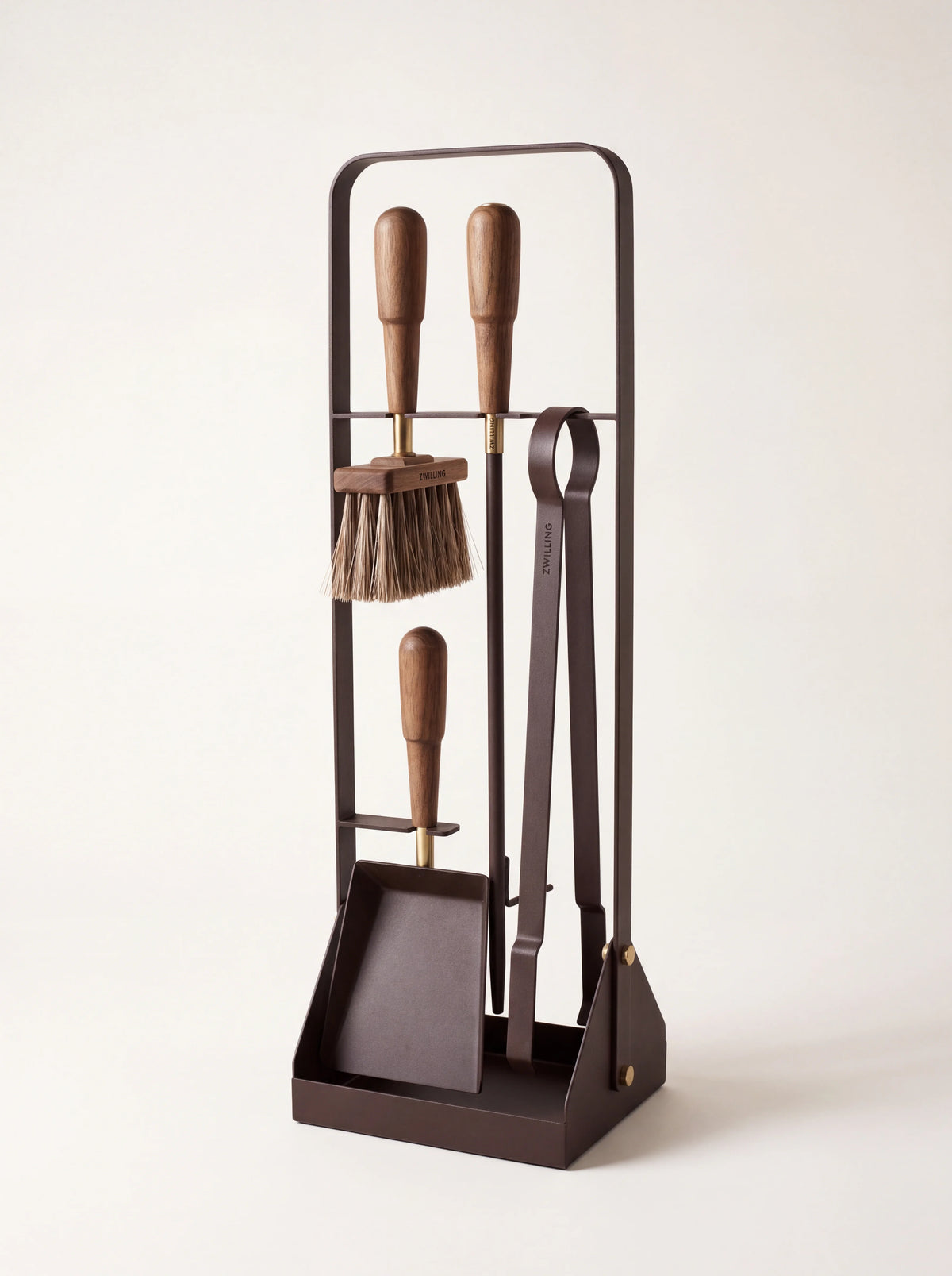 Metal fireplace tool set on a dark frame with walnut handles, holding a brush, shovel, tongs and blow poker