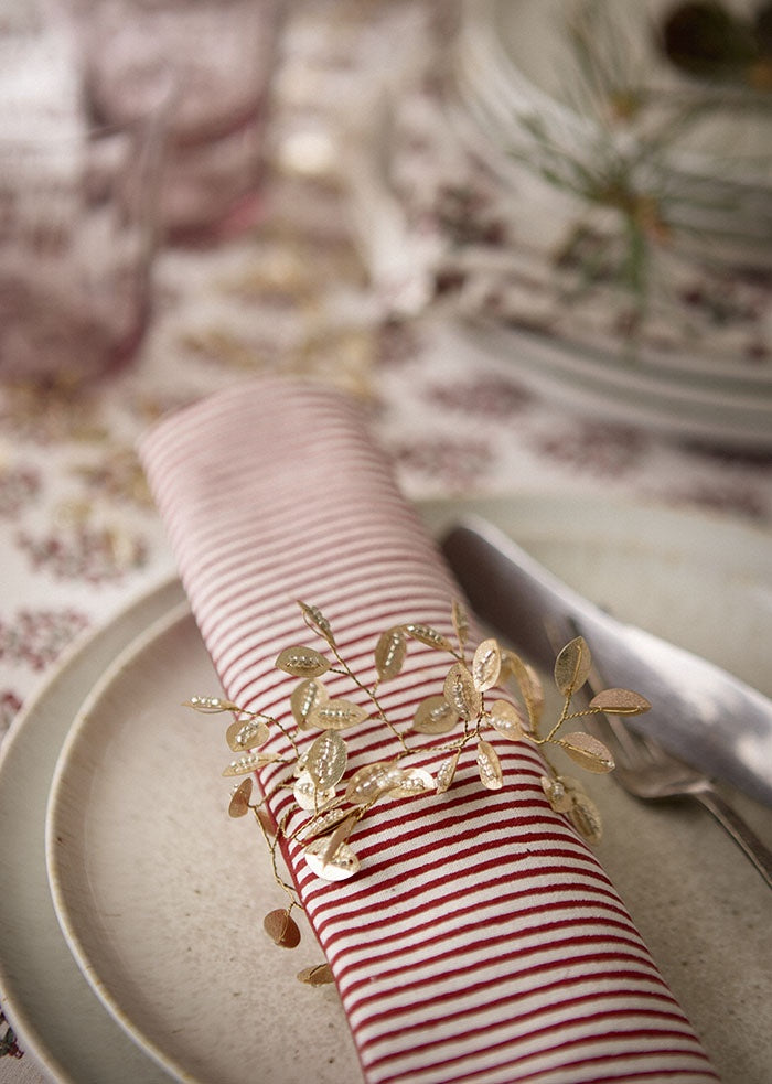 Champagne beaded twig ornament wrapped around a striped napkin on a dinner plate