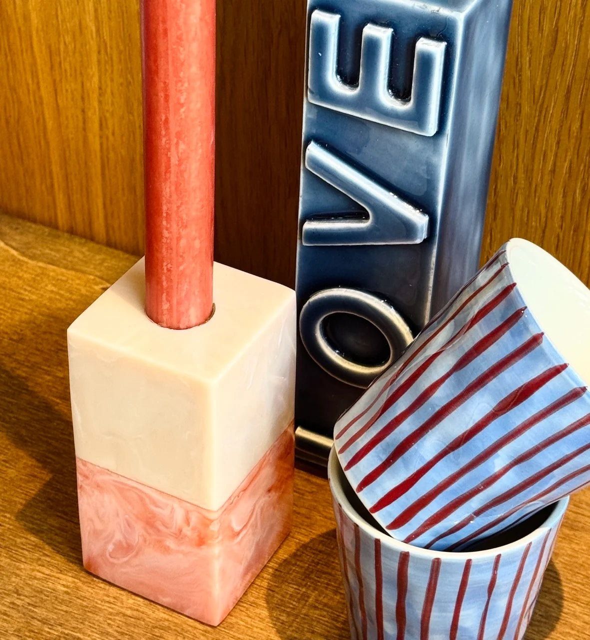 Resin candle holder holding a terracotta taper candle on a wooden surface