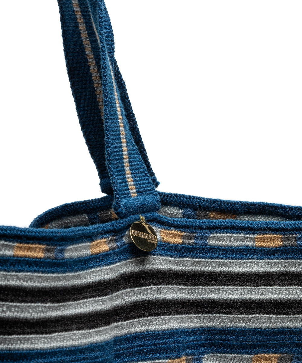 Close-up of the handle base showing a round bronze tag engraved with GUANABANA handmade