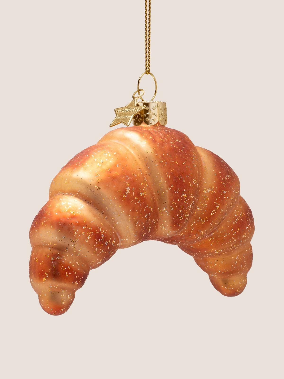 Angled view of the croissant ornament showing its crescent curve and layered pastry folds