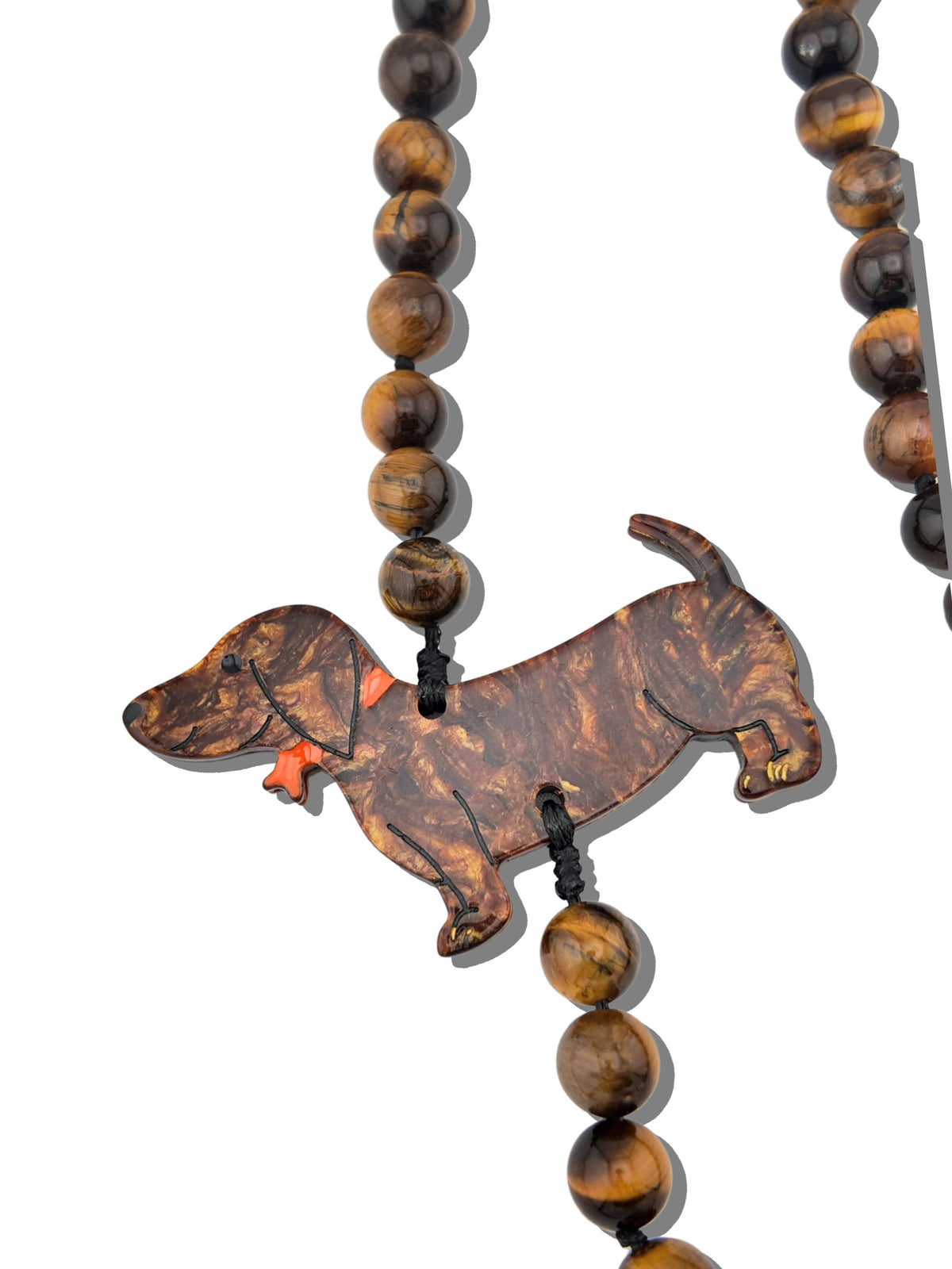 Close-up of the tortoiseshell-pattern dachshund charm with painted red collar strung on gemstone beads