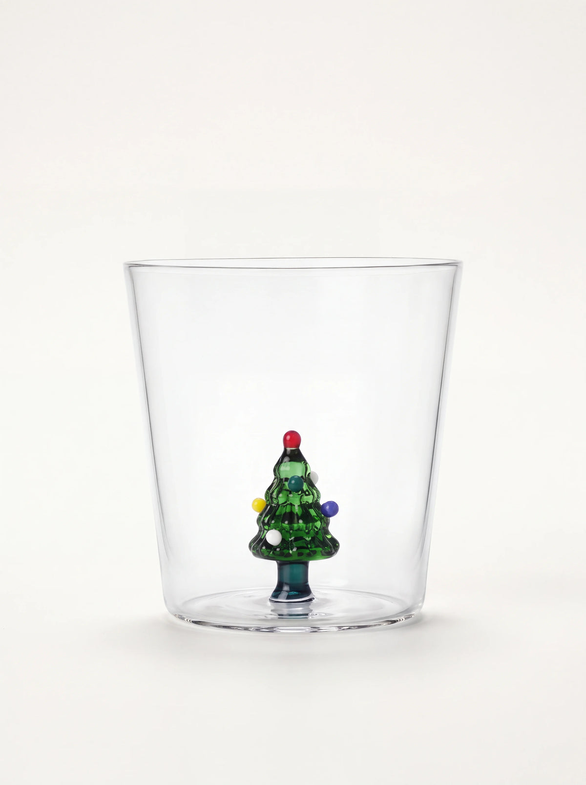 Clear glass tumbler featuring a small green Christmas tree figurine with colourful baubles inside the base
