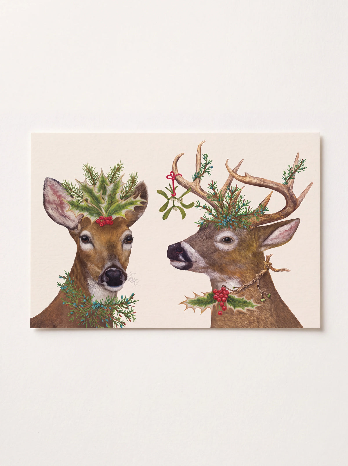 Rectangular paper placemat illustrated with two deer adorned with evergreen foliage, holly and berries