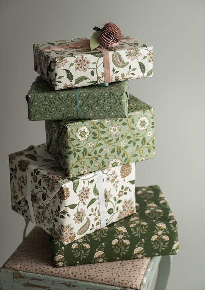 Gift boxes wrapped in the floral wrapping paper, stacked with coordinating green patterned parcels