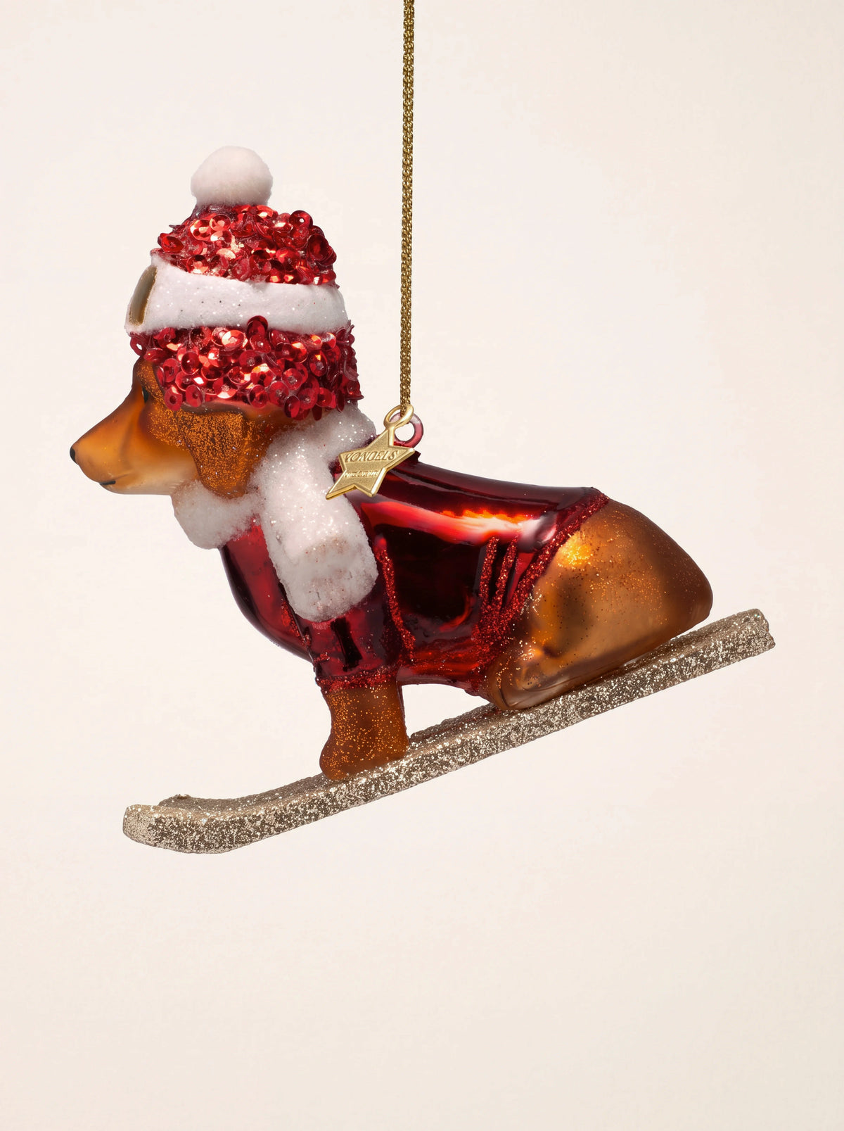 Dog on skis glass ornament wearing a red sequinned hat, white scarf and red jacket on glittered skis
