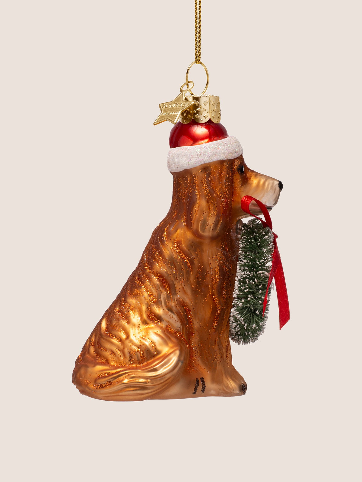 Right profile showing the seated silhouette, glittery coat, and wreath ribbon held in the mouth