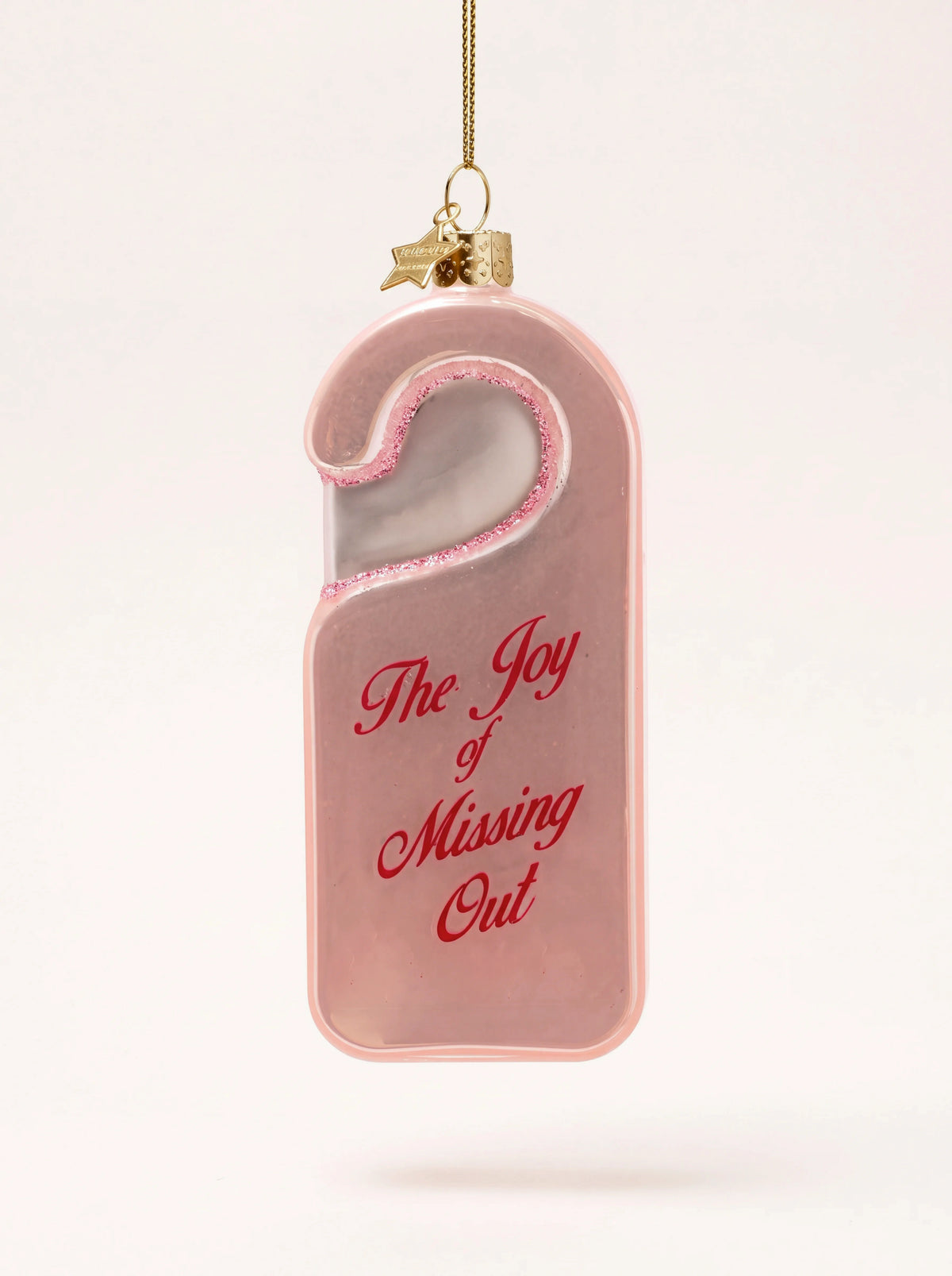 Pink glass door hanger ornament with glitter trim and red lettering reading 'The Joy of Missing Out