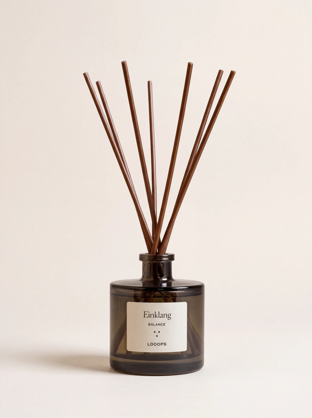 Tinted glass reed diffuser with brown paper reeds, labelled Einklang BALANCE LOOOPS