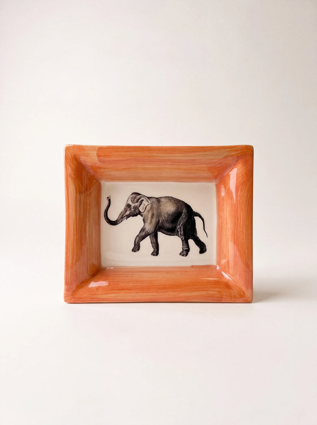Rectangular glazed ceramic dish with a hand-painted orange rim and a monochrome elephant illustration