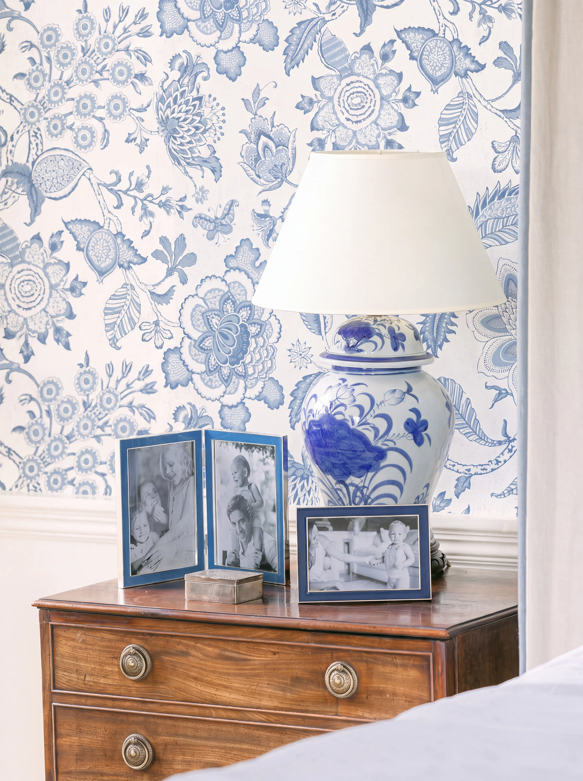 Navy enamelled frame displayed horizontally on a wooden chest of drawers next to a blue ceramic lamp