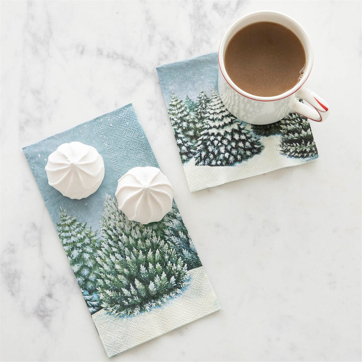 Paper guest napkin on marble alongside treats and a coffee mug, showing embossed texture and scale