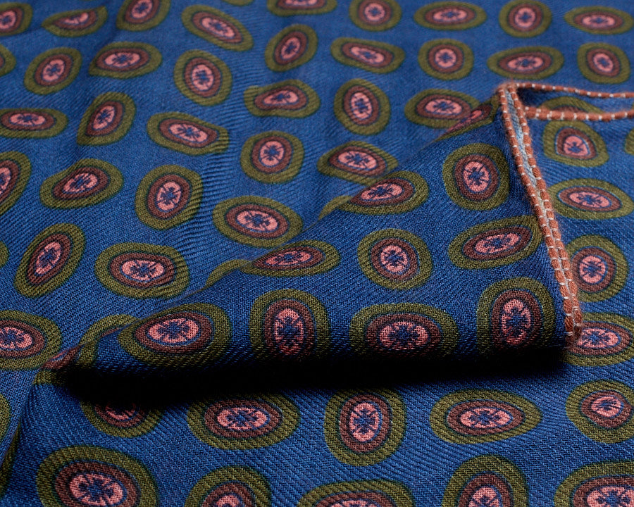 Blue wool scarf folded to show the printed oval eye motif, fine weave, and contrasting stitched border