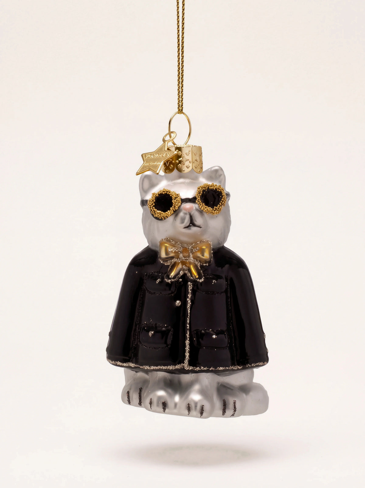 White glass cat Christmas ornament wearing sunglasses, a gold bow tie and a black jacket with glitter trim