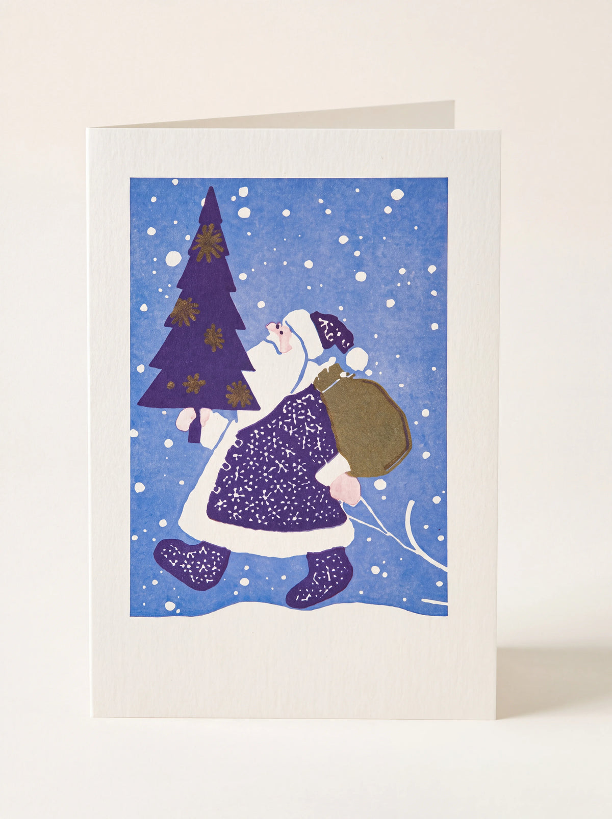 Folded paper card illustrated with Father Christmas carrying a fir tree and sack against a snowy blue background