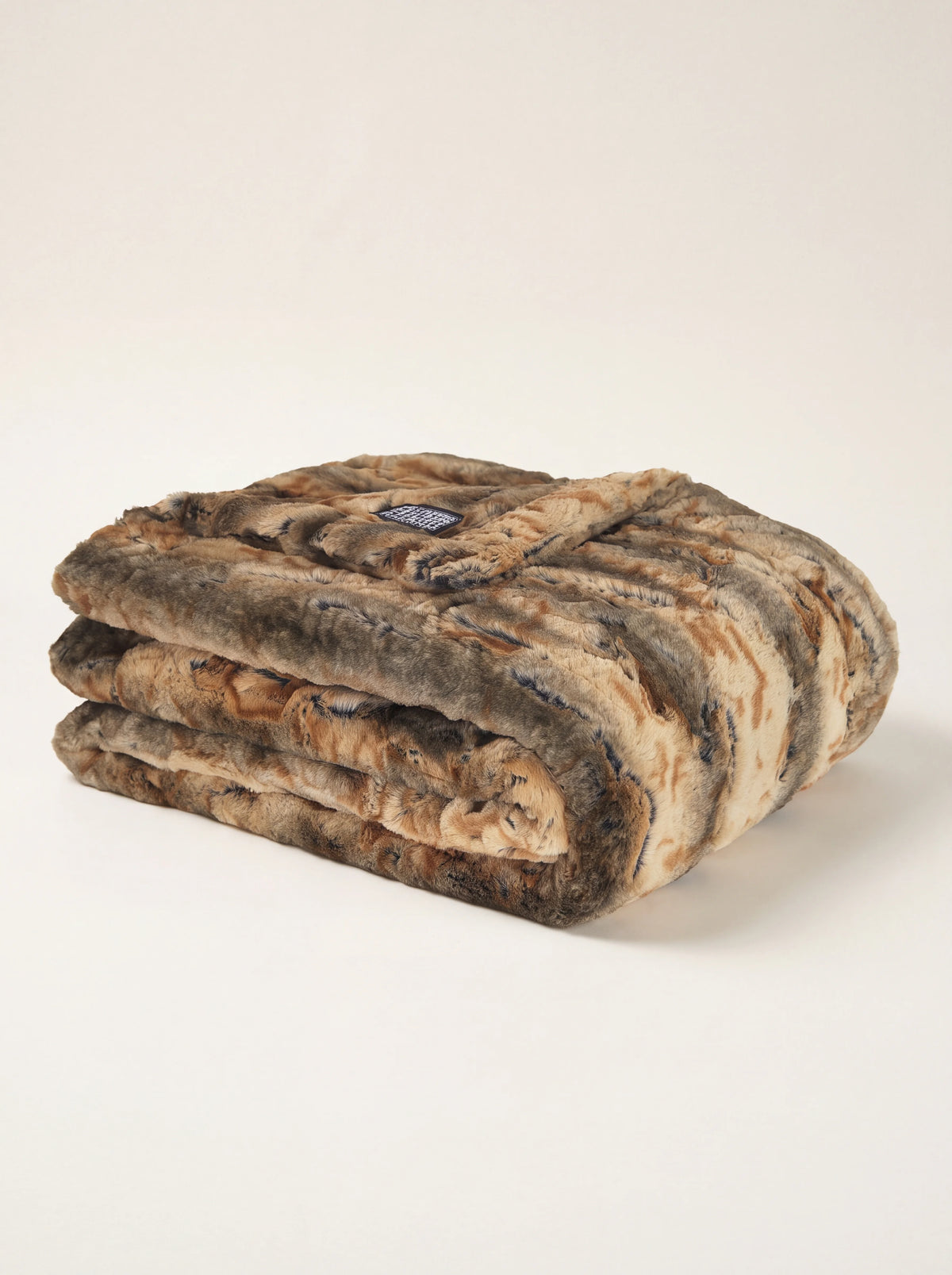 Striped faux fur blanket in tones of brown and beige, folded in layers