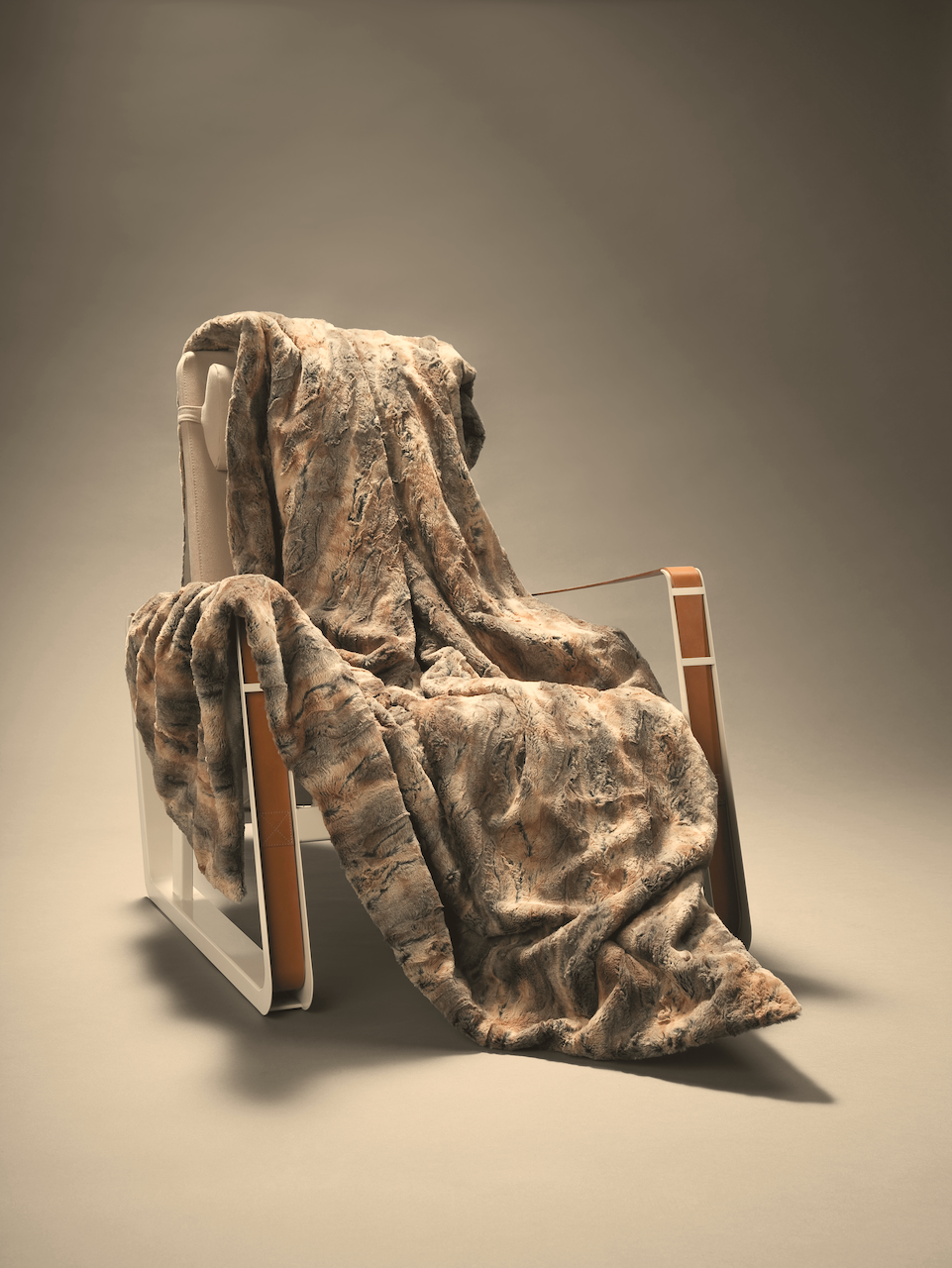 Striped faux fur blanket draped over an armchair, showing its drape and textured pile