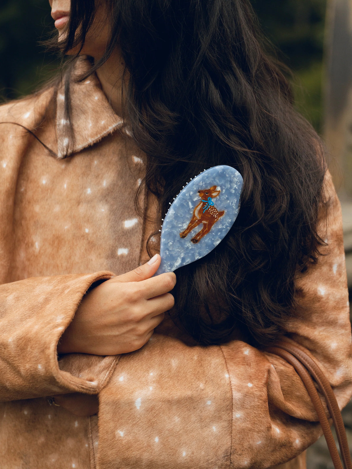 Fawn acetate hairbrush held in one hand against hair, showing its scale and bristles