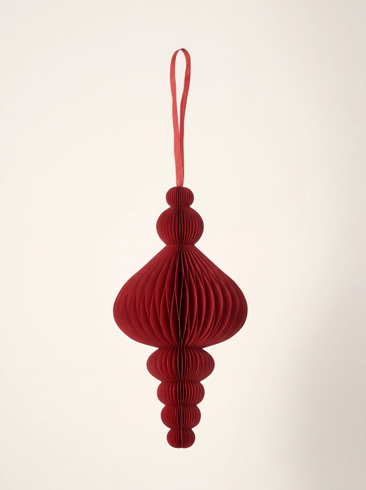 Ruby red paper honeycomb ornament with a flared finial silhouette and ribbon hanging loop