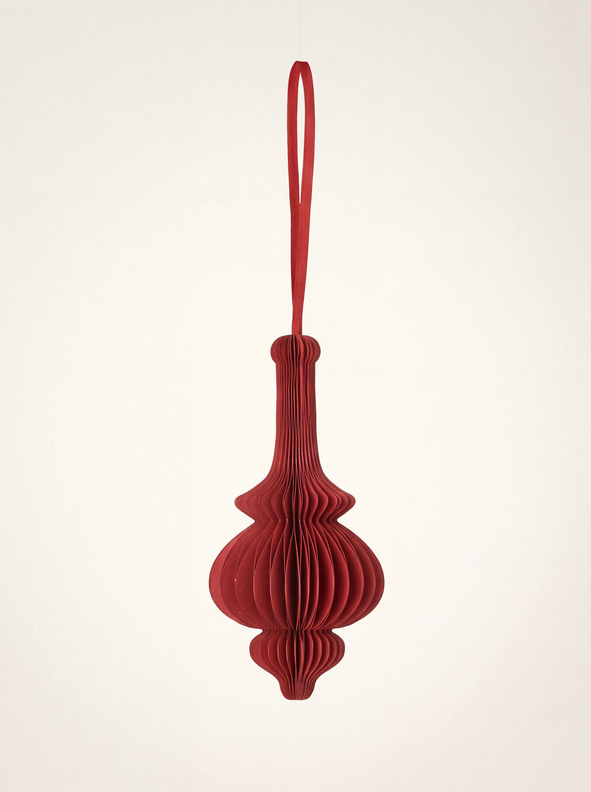 Ruby red paper honeycomb ornament with a flared silhouette, pleated folds and hanging ribbon