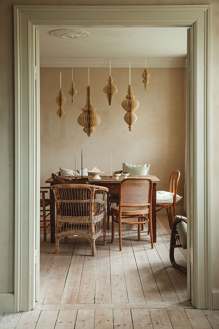 Several paper honeycomb ornaments suspended at varying heights above a wooden dining table