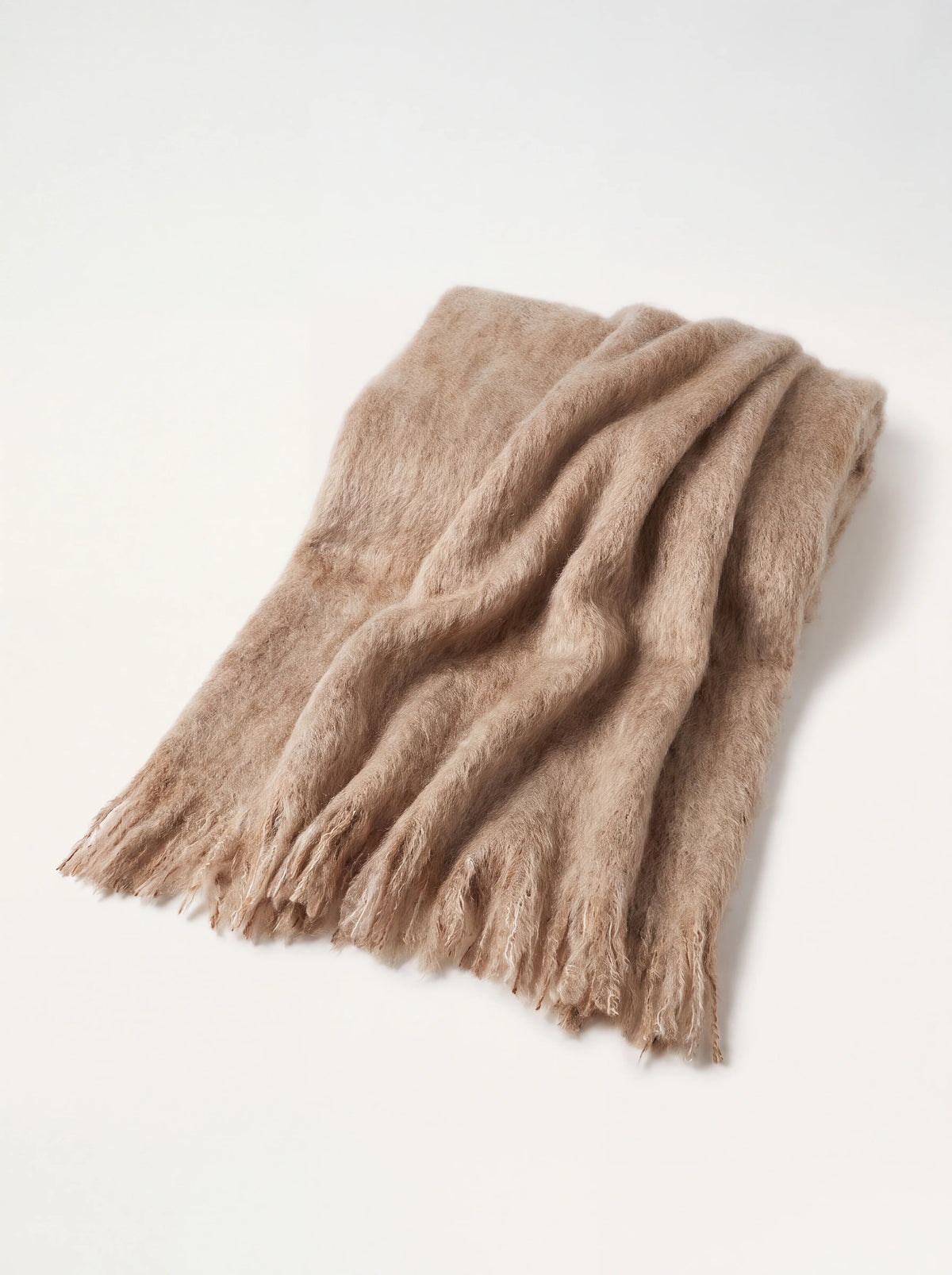 Brushed mohair-wool throw in warm beige earth tones, folded with fringed edges