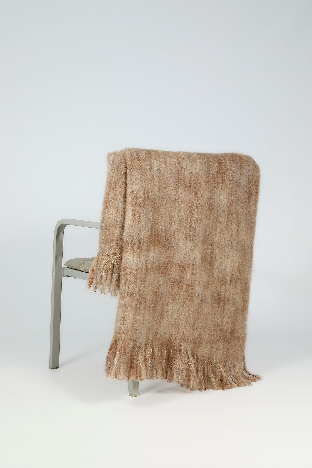 Mohair-wool throw draped over the back of an armchair, showing its length and fringed hem