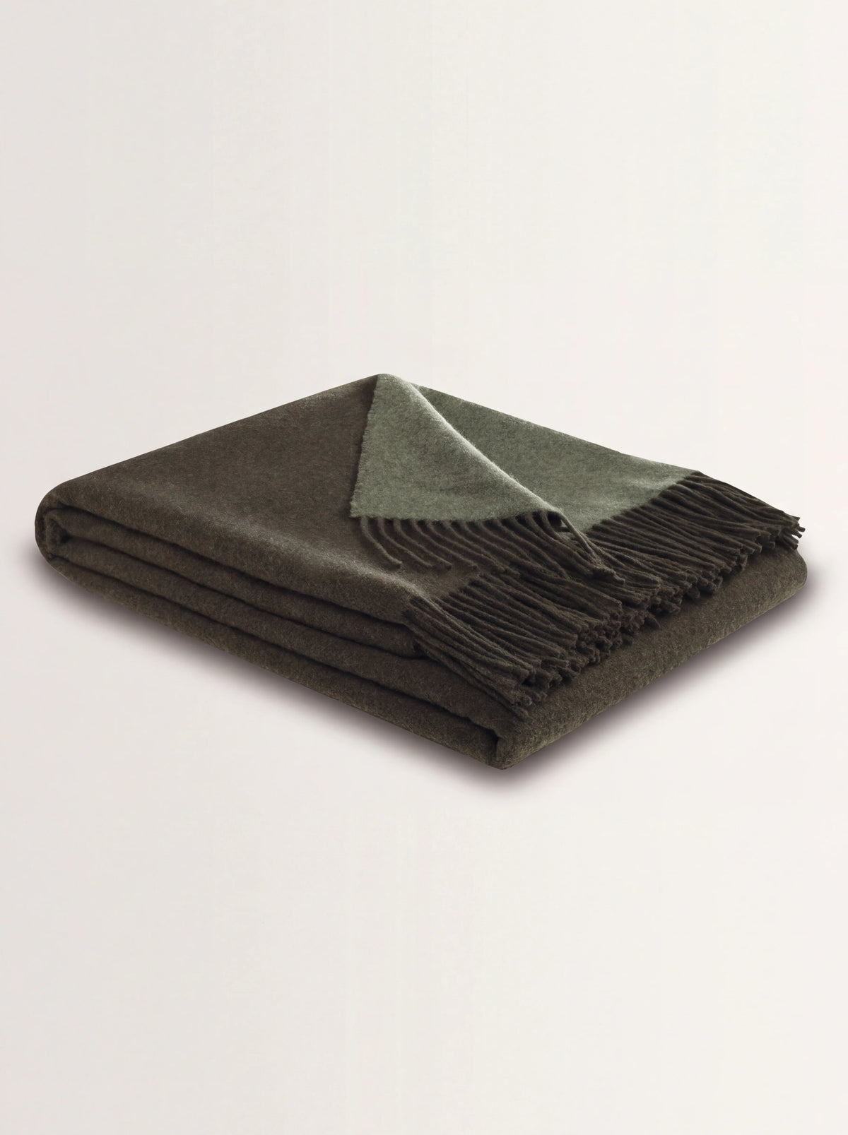 Dark green wool and cashmere blanket folded to show the fringe and contrasting sage green reverse
