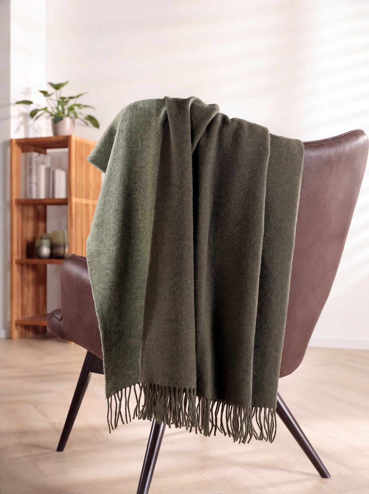 Wool and cashmere blanket draped over the back of an armchair, showing its soft folds and fringes