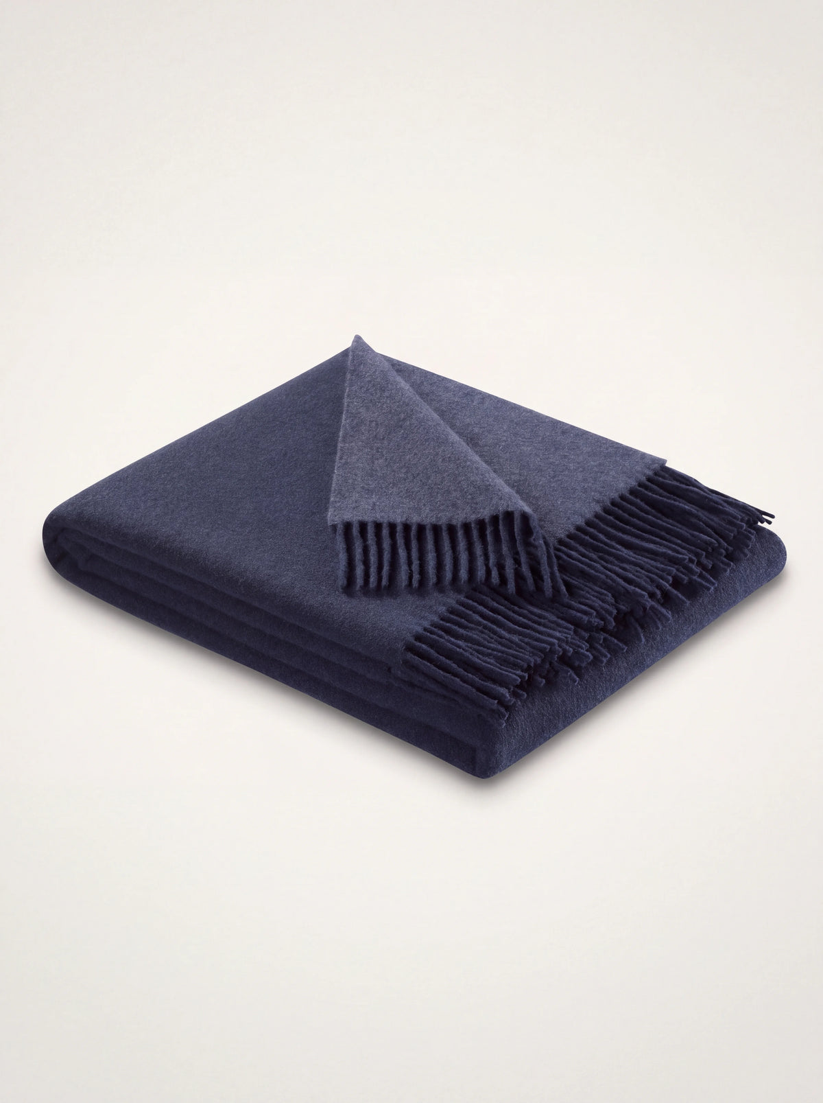 Two-tone navy and denim wool blanket folded to show both shades and fringed edges