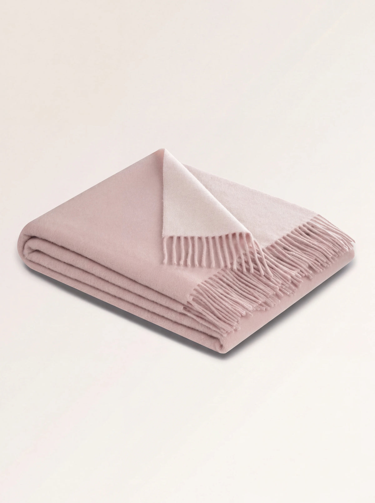 Folded rose wool blanket with fringed trim, turned back to show the ecru reverse
