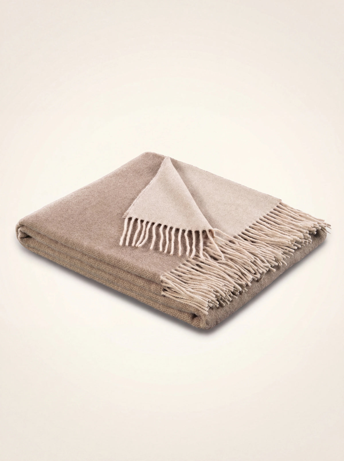 Folded two-tone wool and cashmere throw in sand and natural tones with fringed ends