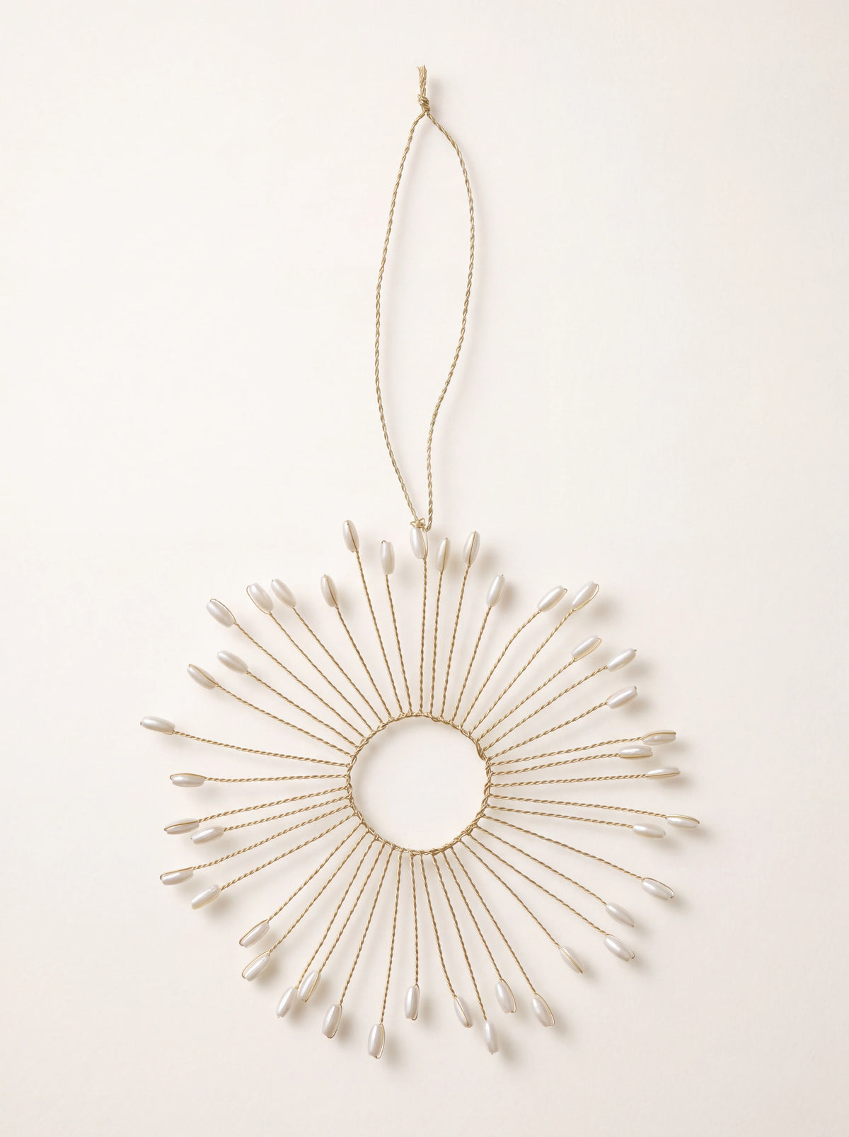 Round wire ornament with cream pearl beads radiating from a central ring, hanging from a cord loop