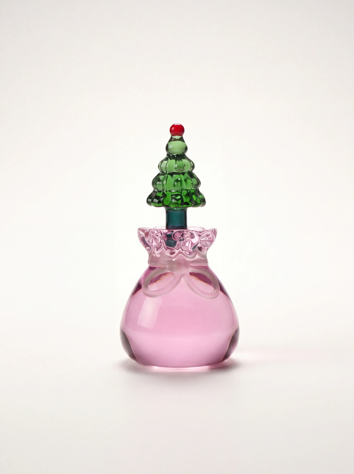 Glass candle holder with a pink sack-shaped base and a green Christmas tree topped with a red sphere