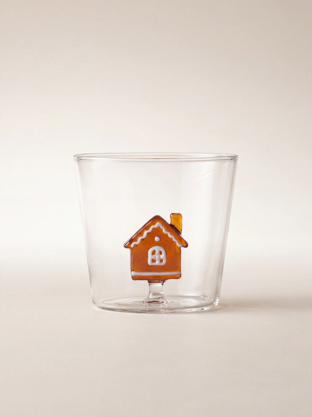 Clear borosilicate glass tumbler with an amber gingerbread house figurine featuring white details
