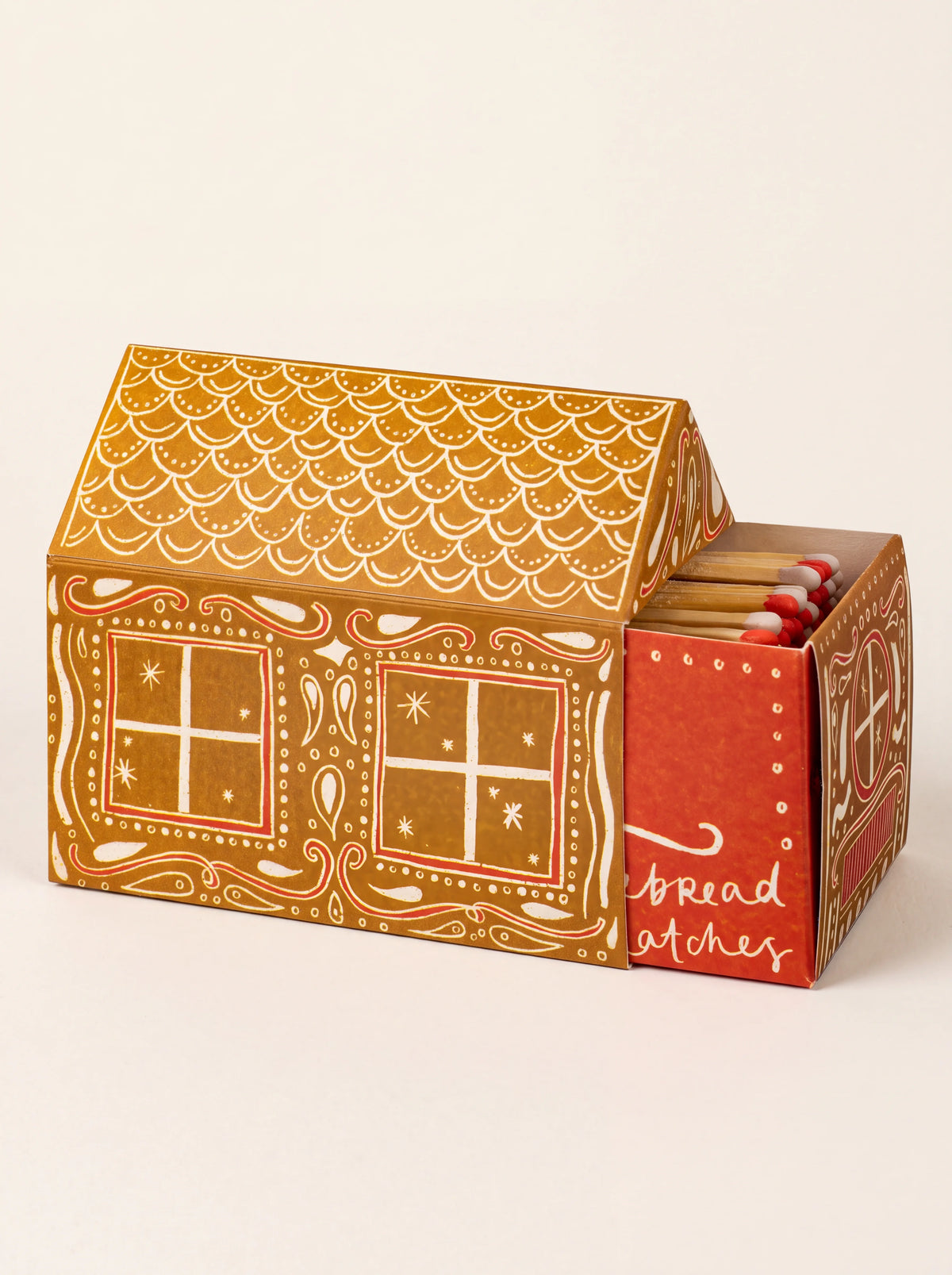 Gingerbread-house-shaped matchbox with its sliding drawer pulled open to reveal red-and-white tipped matches