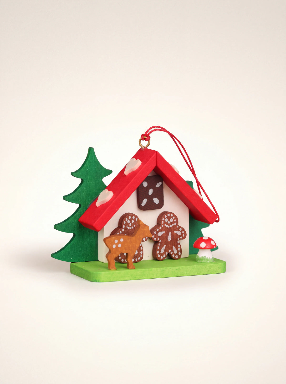 Painted wooden gingerbread house ornament with a red roof, gingerbread figures, fawn, fir tree and hanging loop
