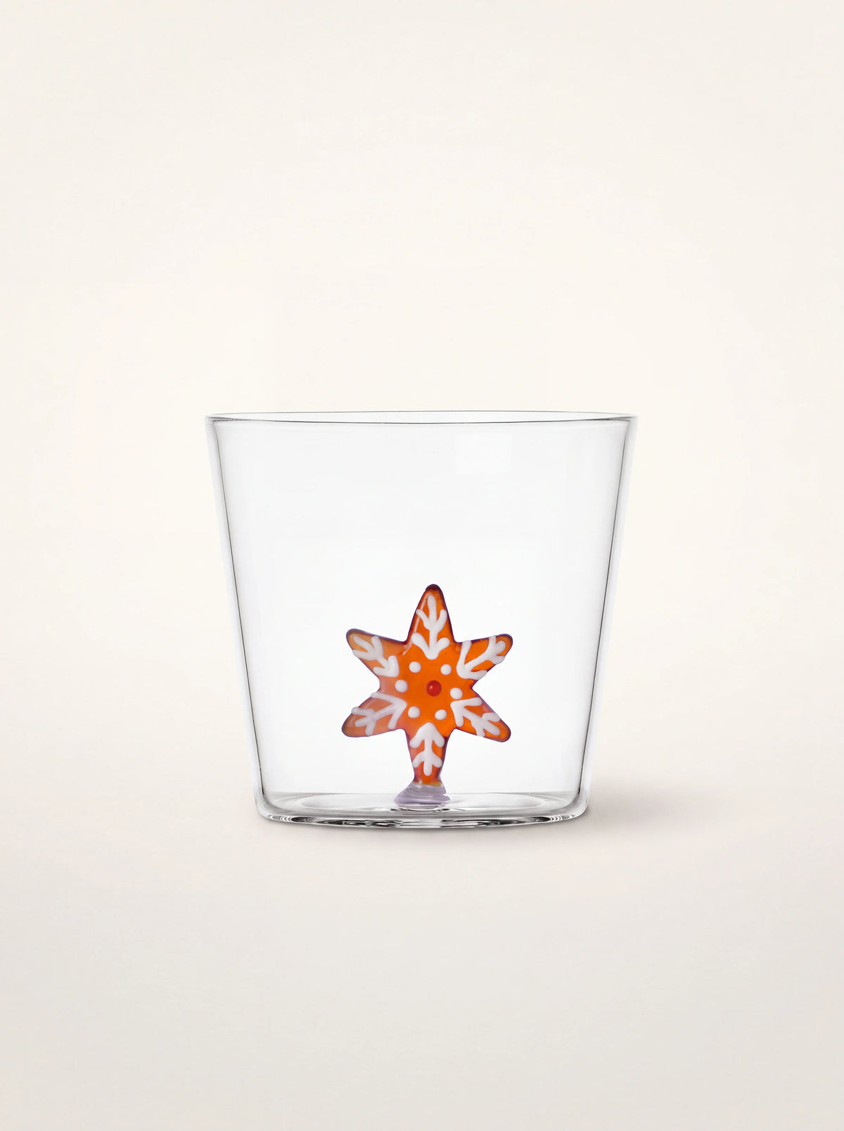 Clear glass tumbler with an amber and white gingerbread snowflake figurine inside the base