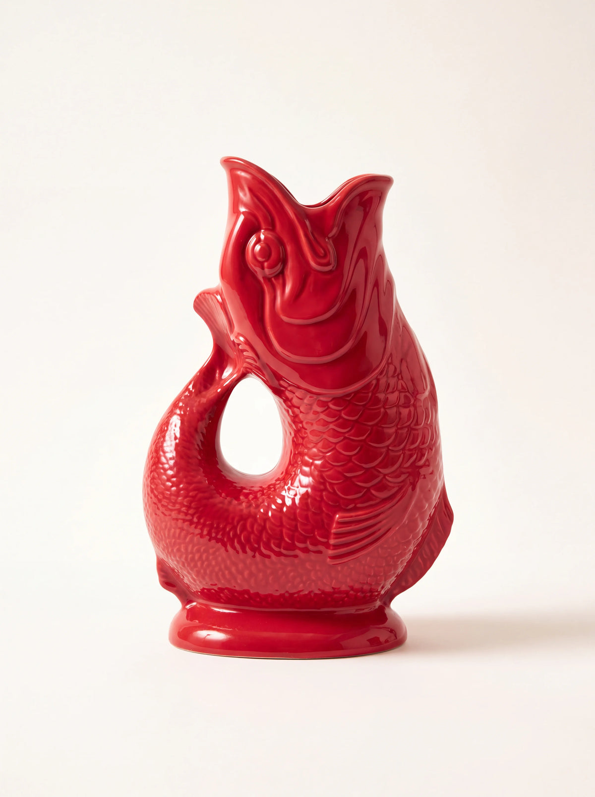 Cranberry red glazed porcelain fish jug with an open-mouth spout and curved tail handle