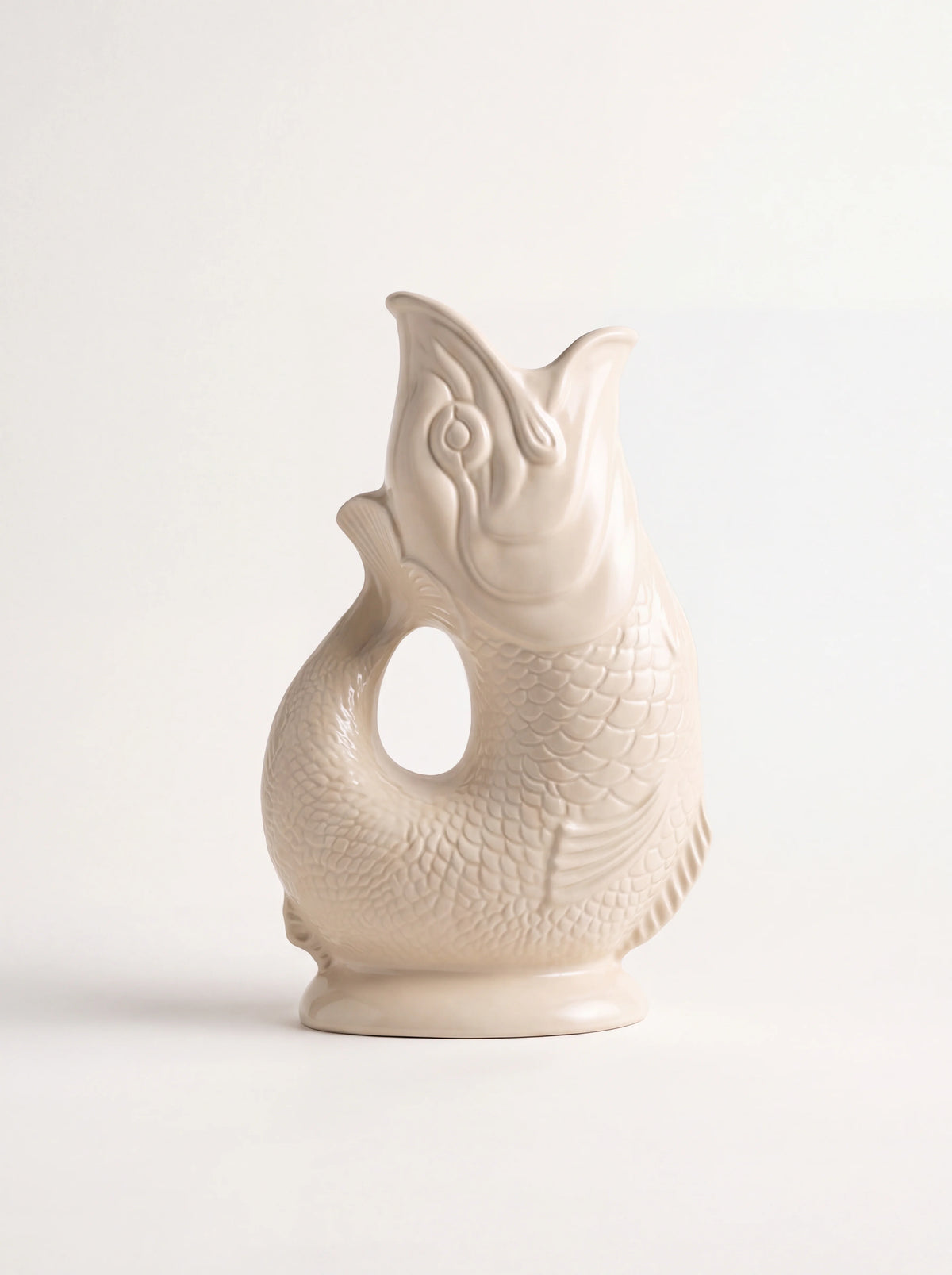 Cream glazed ceramic gluggle jug shaped like a fish with an open-mouth spout and tail handle