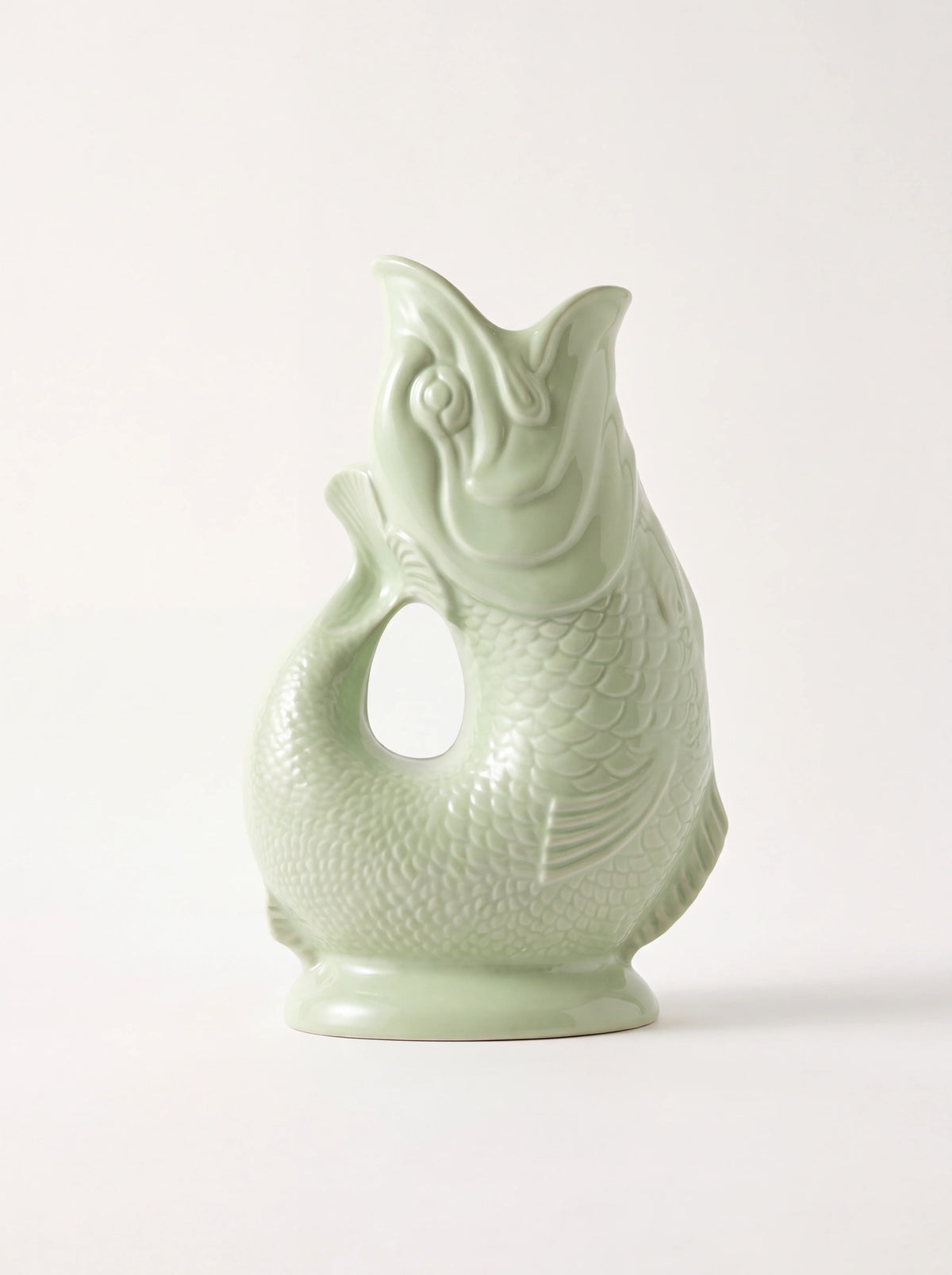 Fish-shaped gluggle jug in pale pistachio green glazed porcelain with embossed scales and open mouth spout