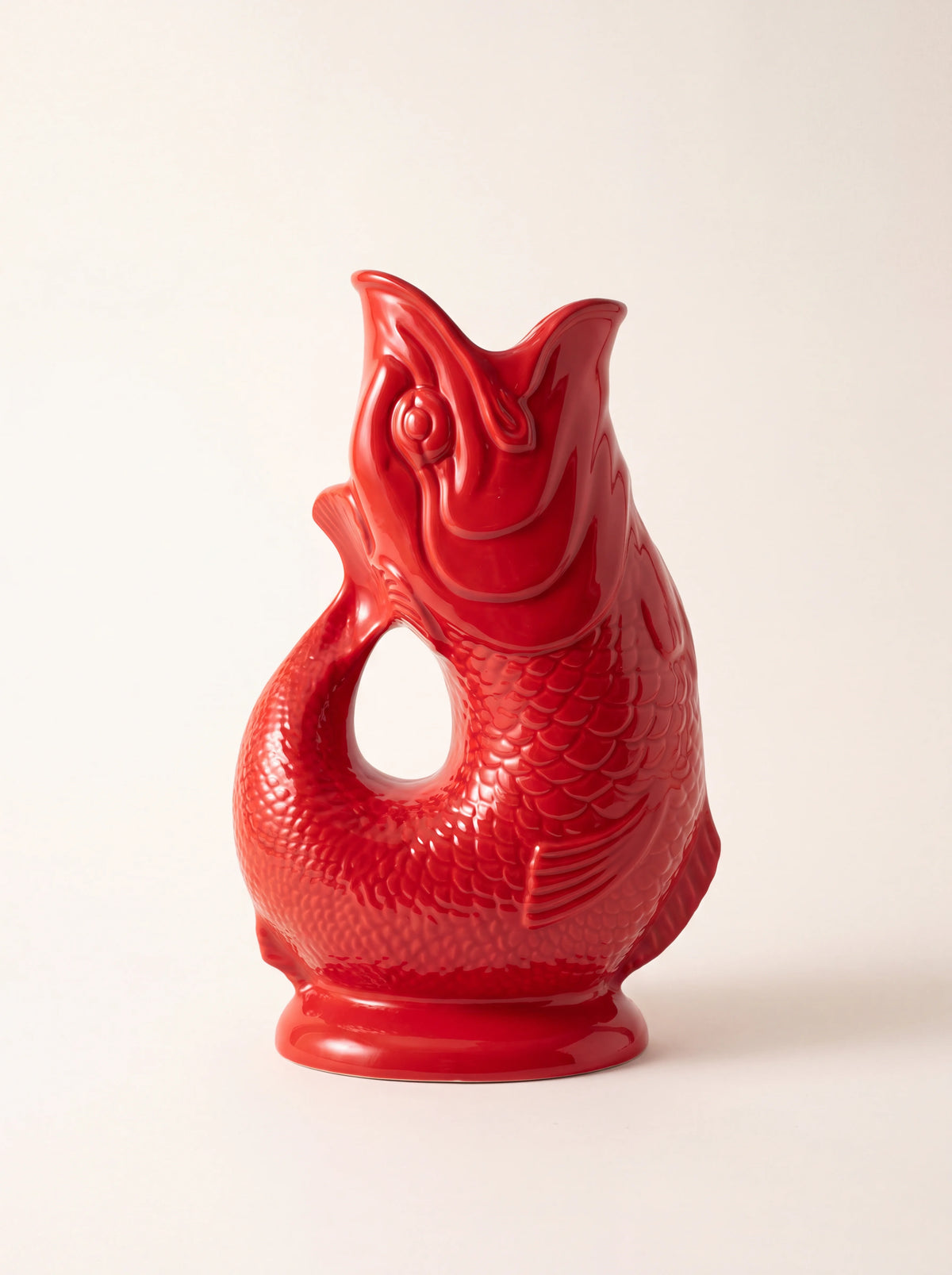 Red glazed porcelain gluggle jug shaped like a fish with an open-mouth spout and curved tail handle
