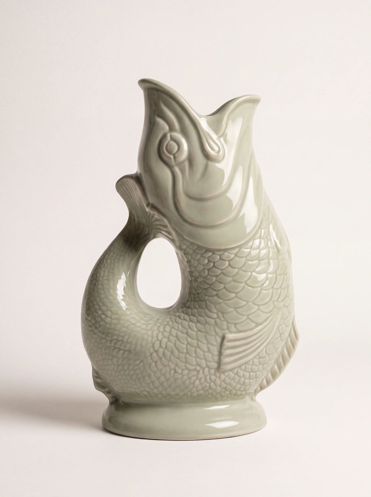 Sage green glazed porcelain fish jug with an open mouth spout and curved tail handle