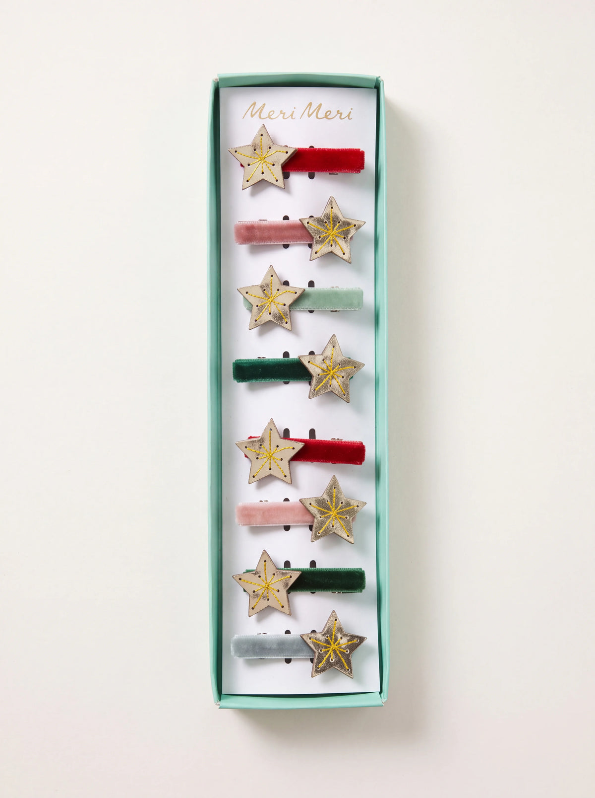 Set of eight hair clips with assorted velvet ribbons and stitched metallic gold stars, displayed in a box
