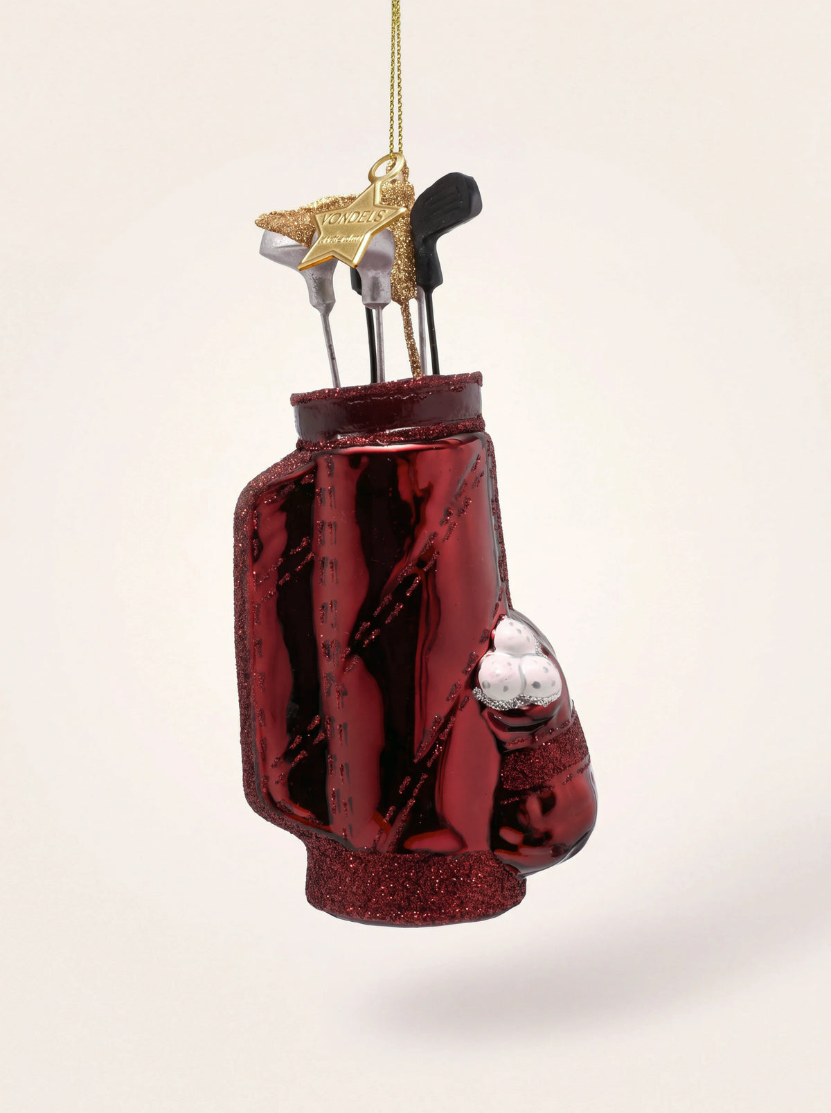 Burgundy glass golf bag ornament with silver clubs, glitter trim and three golf balls in the pocket