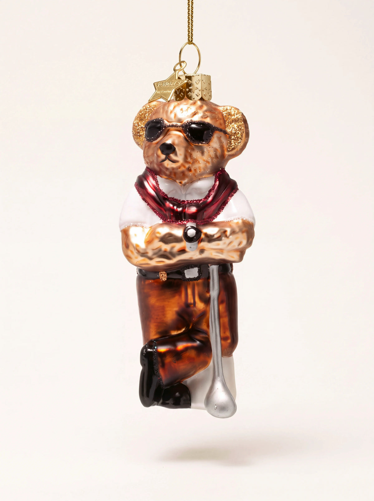 Glass bear ornament wearing sunglasses, a white shirt and draped red jumper, leaning on a golf club